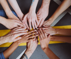 A close-up image of 10 individual hands touching to signify cooperation