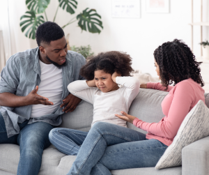 Parents shouting at child (aged around 6) who is covering her ears. 