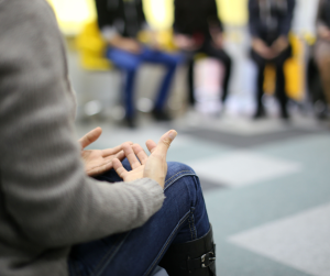 A close up of group a group therapy session with only hands and legs visible. 