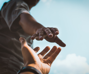 A hand reaching out to help lift somebody up. 