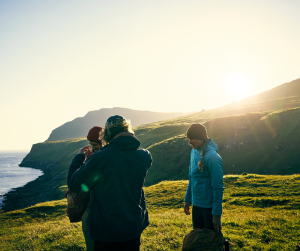 Three walkers on a coastal hillside at dusk. 