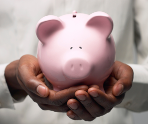 Hands holding a traditional pink piggy bank