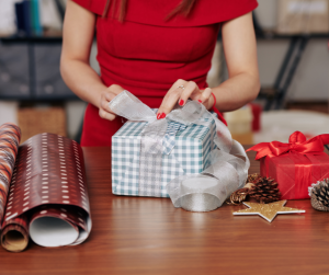 Close up of a lady wearing a red dress and she wraps Christmas presents. 