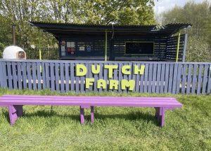 Dutch Farm exterior, a small wooden building behind a painted fence with a sign reading 'Dutch Farm'. 