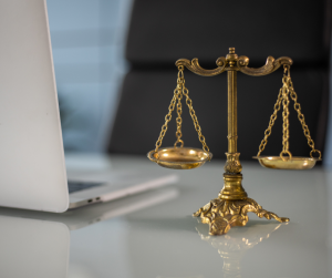 Close up of the scales of justice, next to an open laptop. 