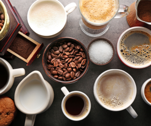 A birds eye vew of various coffee cups, coffee beans, milk and sugar. 