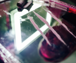 A close up off three lines of cocaine on a mirror. 