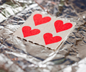 Close up of four LSD / acid tabs on foil. LSD tabs are in the form of red hearts. 