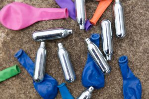 Close up of discarded nitrous oxide canisters and balloons, signifying laughing gas use. 