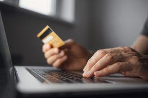 Close up of male hands, using his bank card to make a purchase on a laptop. 