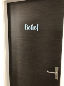 A closed door with the message 'Belief' in bluer stencil.